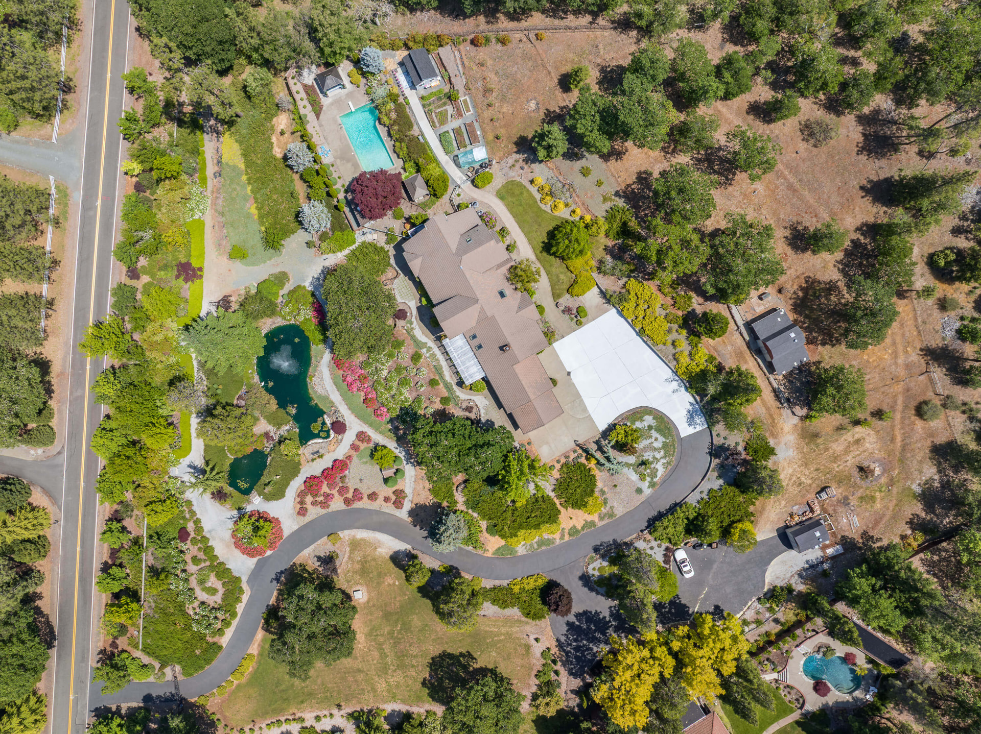 Overhead view of the house, ponds, pool, and drive across the property