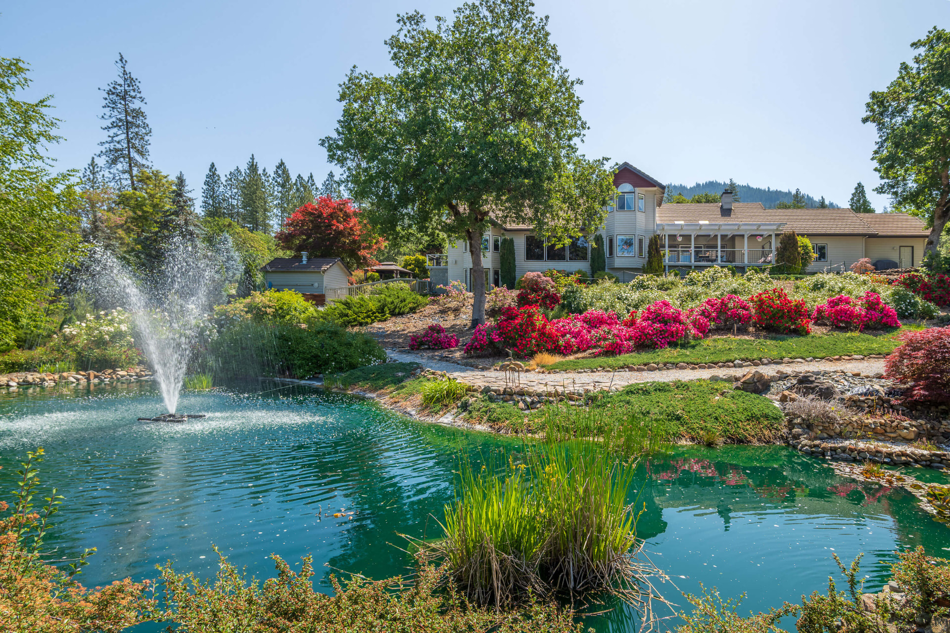 Pond with a spray fountain and rock cascade beside planted beds