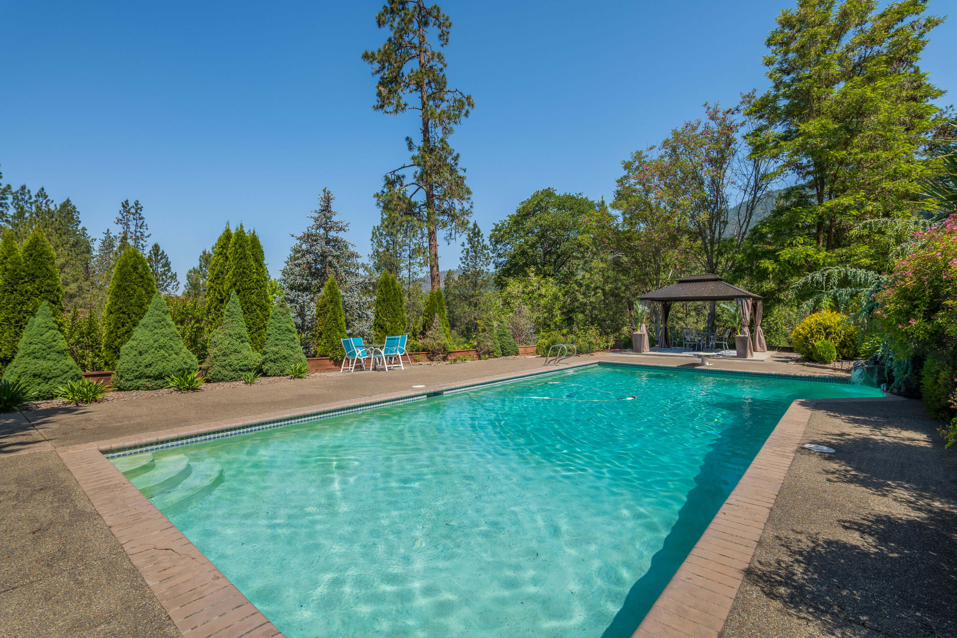 In-ground pool with lounge chairs and a gazebo at the far end